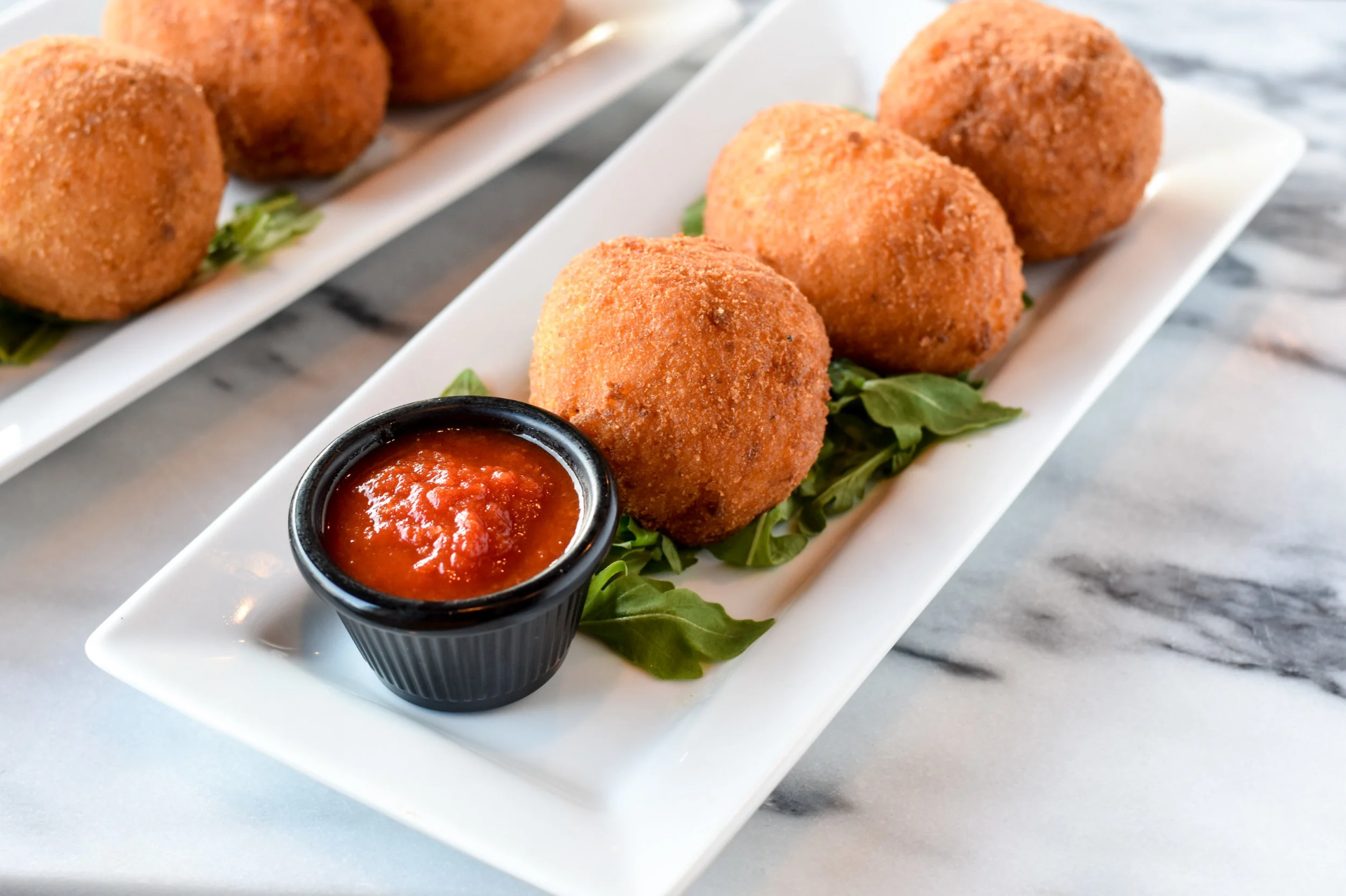 Trays of handmade arancini prepared for wholesale food service